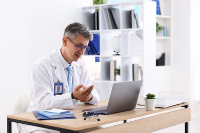 Photo of Telemedicine. Doctor having video call with patient via laptop indoors