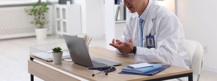 Photo of Telemedicine. Doctor having video call with patient via laptop indoors, closeup
