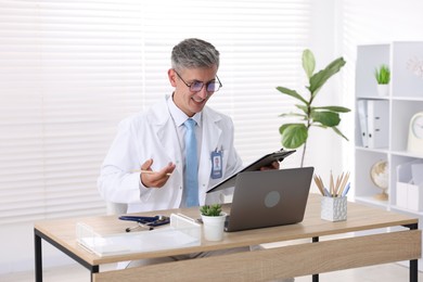 Photo of Telemedicine. Doctor having video call with patient via laptop indoors