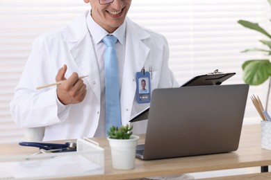 Photo of Telemedicine. Doctor having video call with patient via laptop indoors, closeup