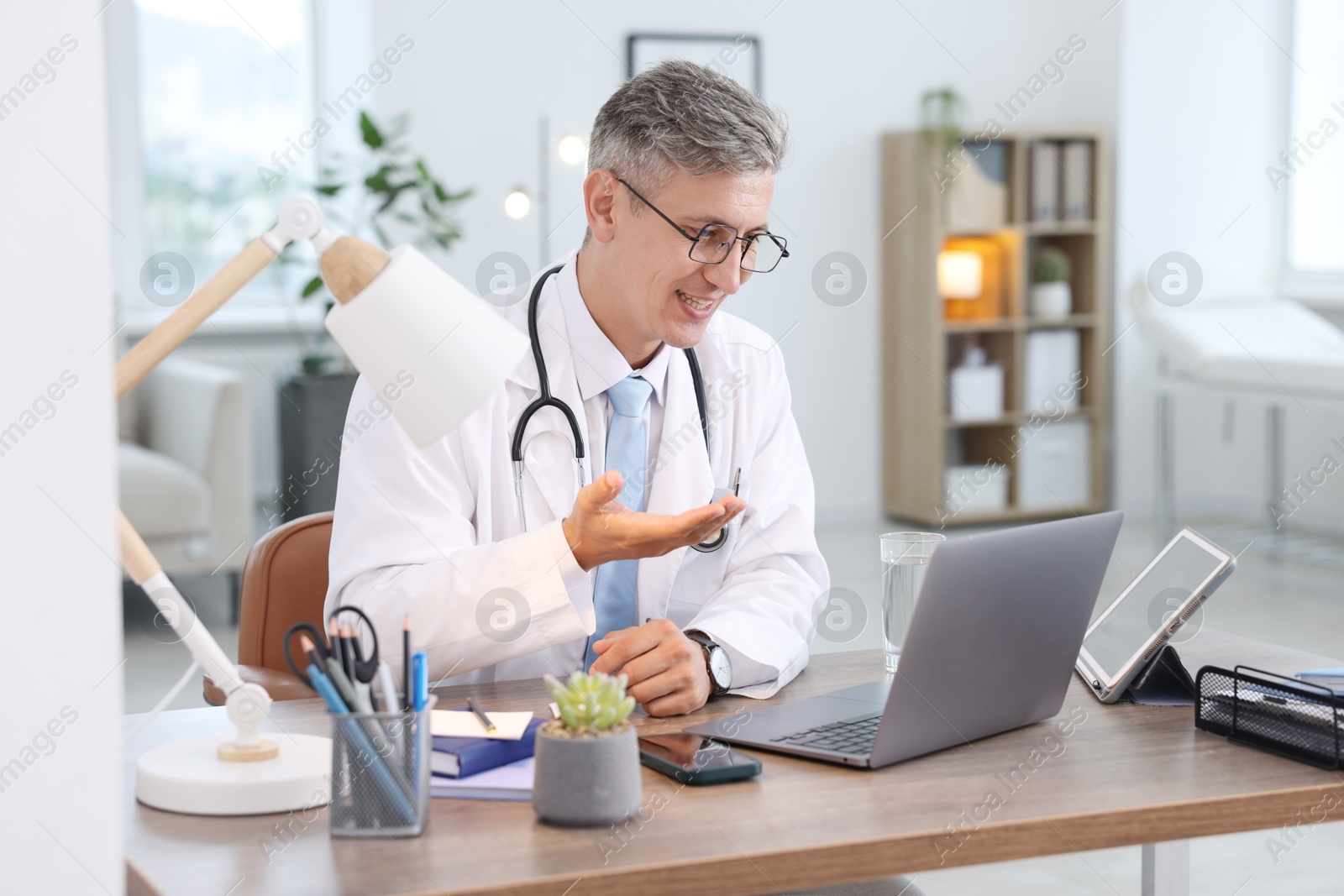 Photo of Telemedicine. Doctor having video call with patient via laptop indoors