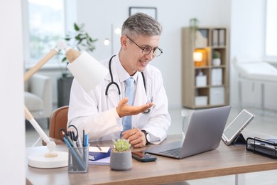 Photo of Telemedicine. Doctor having video call with patient via laptop indoors