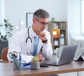 Photo of Telemedicine. Doctor having video call with patient via laptop indoors