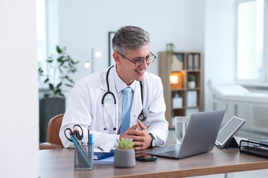 Photo of Telemedicine. Doctor having video call with patient via laptop indoors