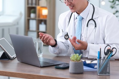 Photo of Telemedicine. Doctor having video call with patient via laptop indoors, closeup