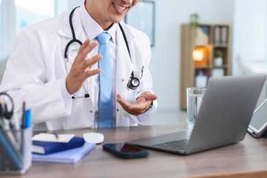Photo of Telemedicine. Doctor having video call with patient via laptop indoors, closeup