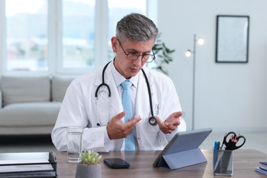 Photo of Telemedicine. Doctor having video call with patient via tablet indoors