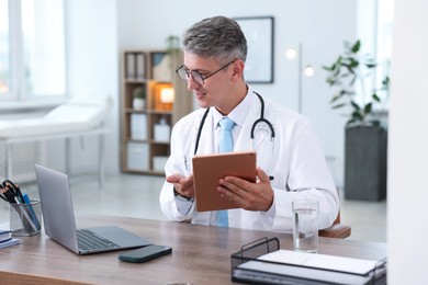 Photo of Telemedicine. Doctor having video call with patient via tablet indoors