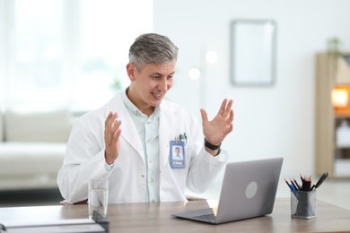 Photo of Telemedicine. Doctor having video call with patient via laptop indoors