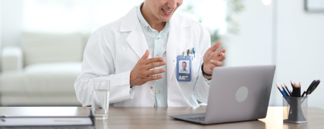Photo of Telemedicine. Doctor having video call with patient via laptop indoors, closeup