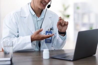 Photo of Telemedicine. Doctor recommending pills to patient during video call via laptop indoors, closeup