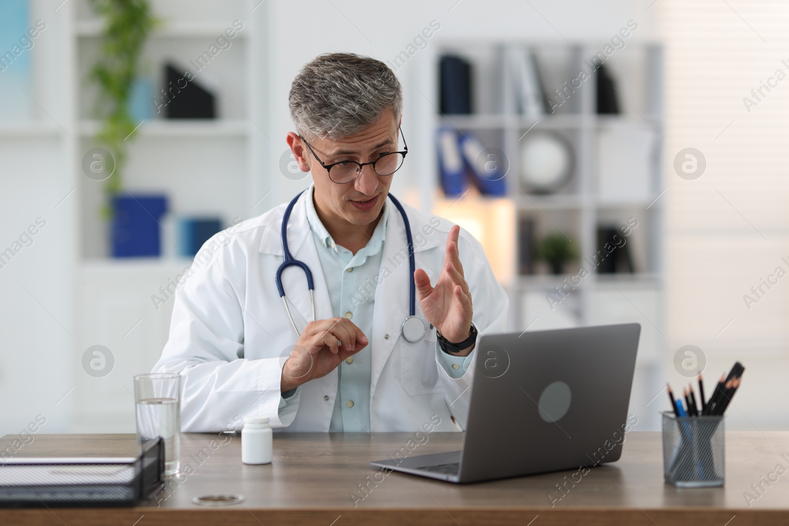 Photo of Telemedicine. Doctor having video call with patient via laptop indoors