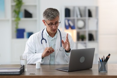 Photo of Telemedicine. Doctor having video call with patient via laptop indoors