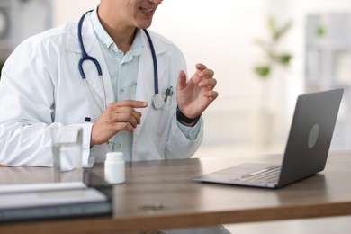 Photo of Telemedicine. Doctor having video call with patient via laptop indoors, closeup