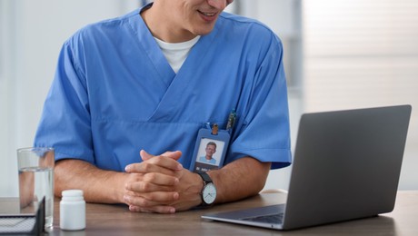 Photo of Telemedicine. Doctor having video call with patient via laptop indoors, closeup