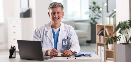Photo of Telemedicine. Doctor making notes while having video call with patient via laptop indoors