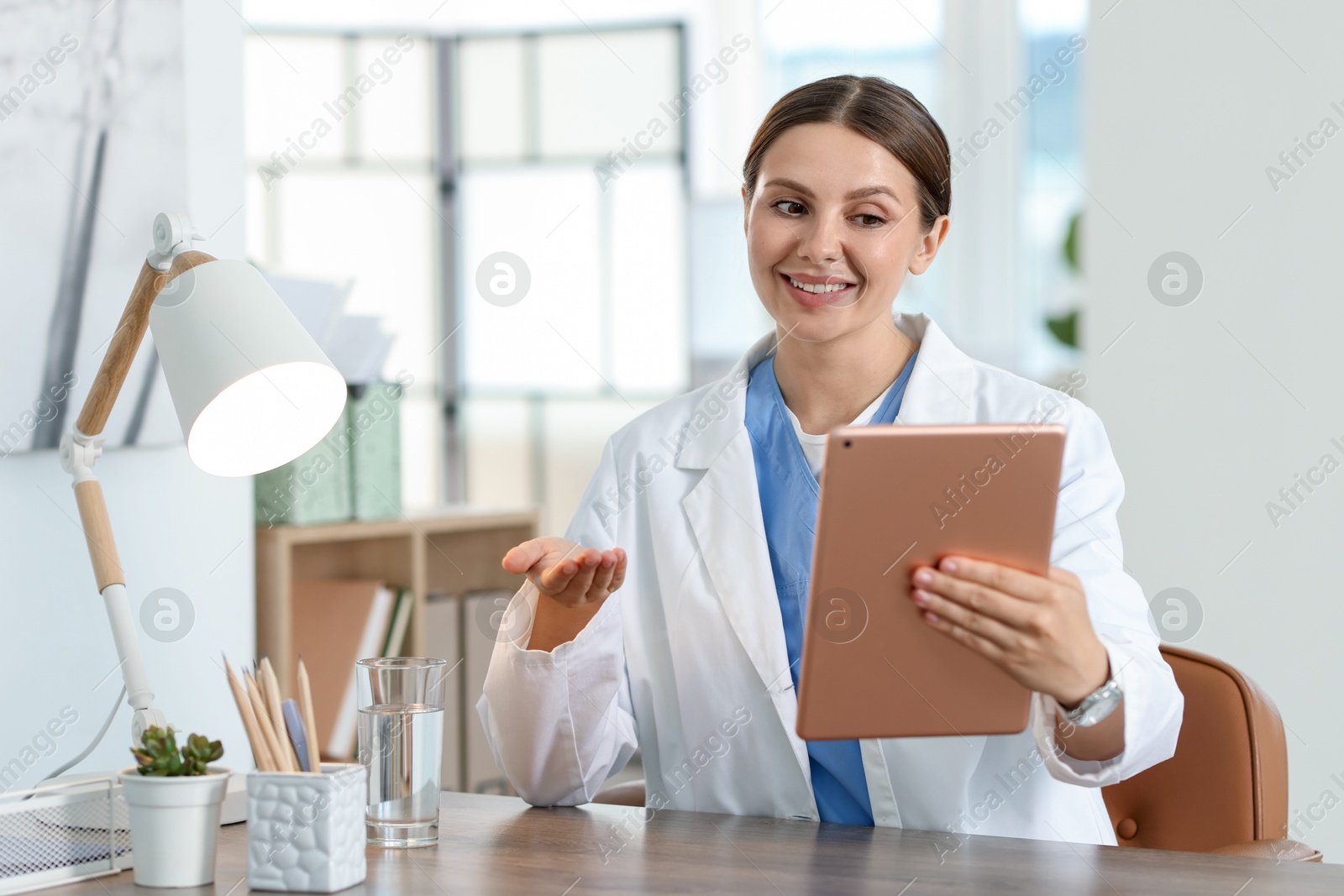 Photo of Telemedicine. Doctor having video call with patient via tablet indoors