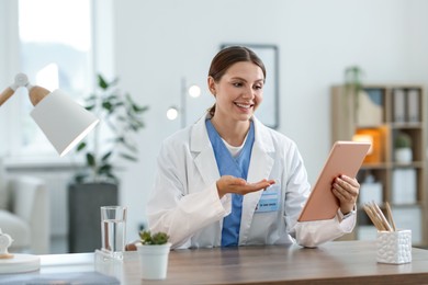 Photo of Telemedicine. Doctor having video call with patient via tablet indoors