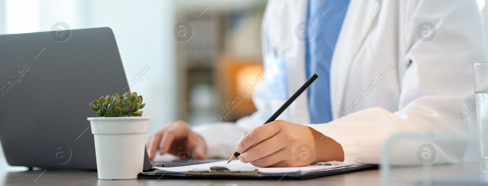 Photo of Telemedicine. Doctor making notes while having video call with patient via laptop indoors, closeup