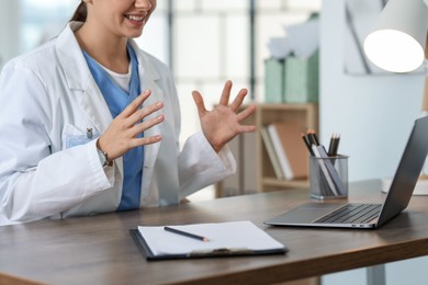 Photo of Telemedicine. Doctor having video call with patient via laptop indoors, closeup