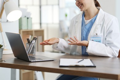 Photo of Telemedicine. Doctor having video call with patient via laptop indoors, closeup