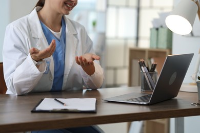 Photo of Telemedicine. Doctor having video call with patient via laptop indoors, closeup