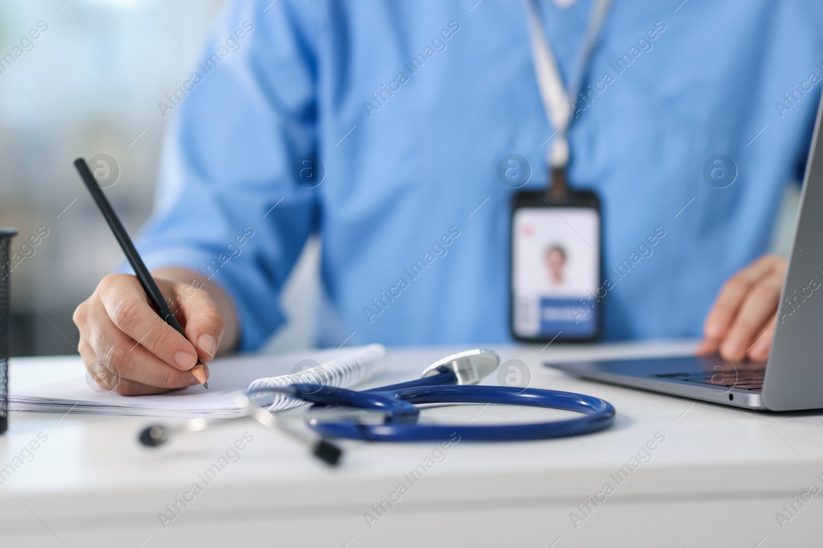 Photo of Telemedicine. Doctor making notes while having video call with patient via laptop indoors, closeup