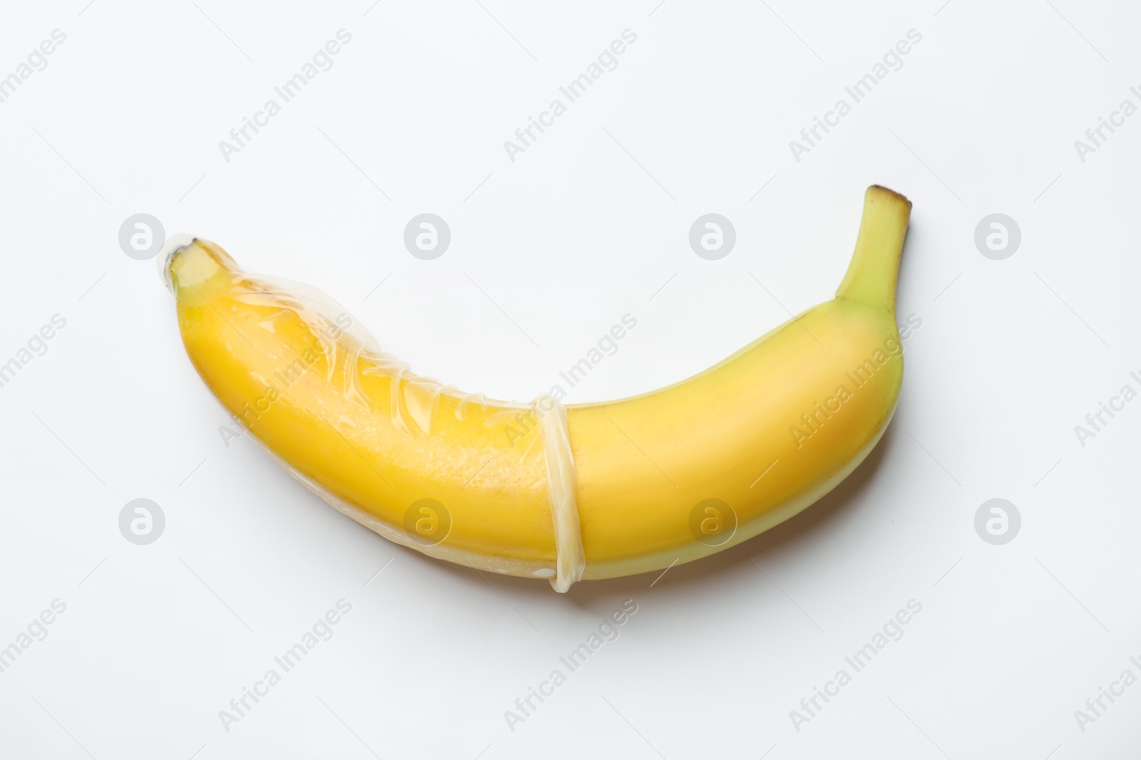 Photo of Sex education. Banana with condom on white background, top view