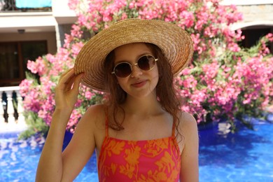 Photo of Girl in straw hat near swimming pool outdoors on sunny day