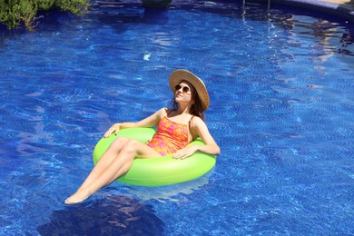 Photo of Girl on inflatable ring in swimming pool outdoors on sunny day