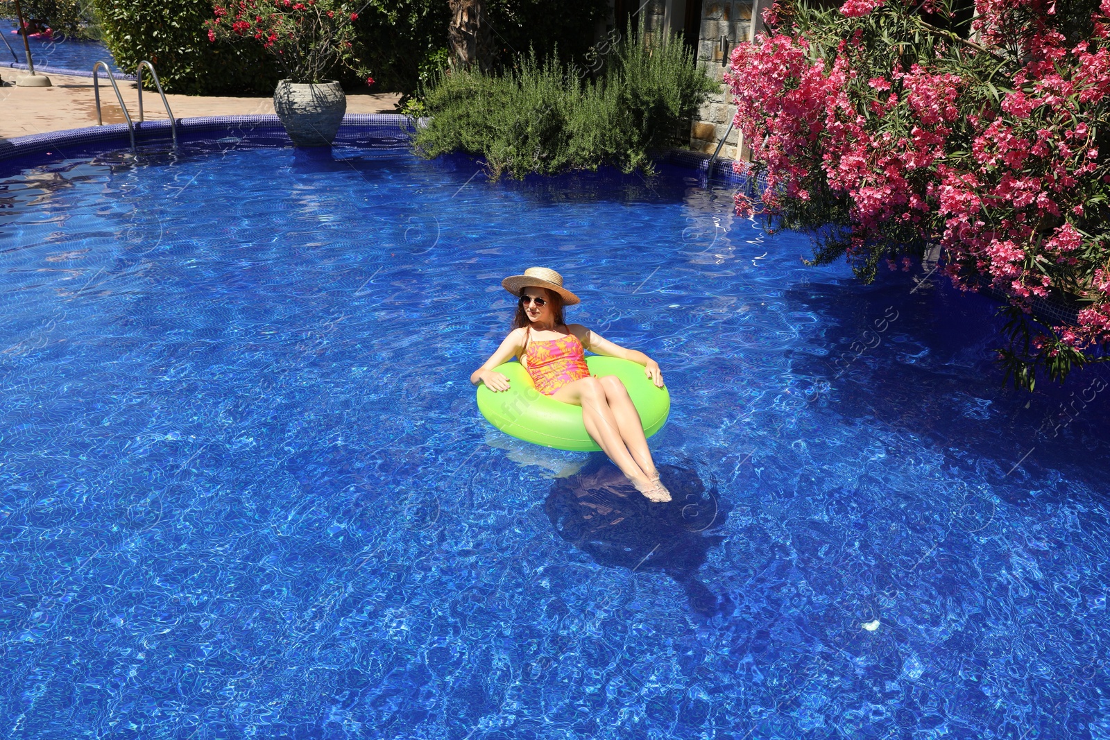 Photo of Girl on inflatable ring in swimming pool outdoors on sunny day, space for text
