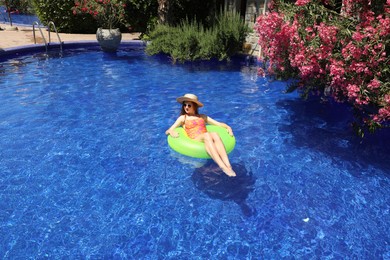 Photo of Girl on inflatable ring in swimming pool outdoors on sunny day, space for text