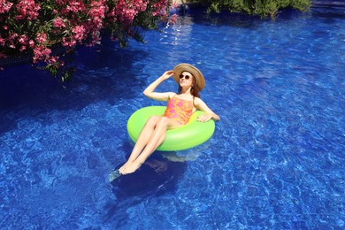 Photo of Girl on inflatable ring in swimming pool outdoors on sunny day