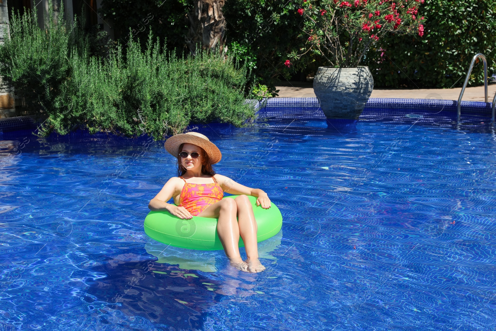 Photo of Girl on inflatable ring in swimming pool outdoors on sunny day, space for text
