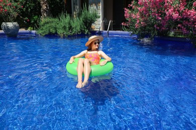 Photo of Girl on inflatable ring in swimming pool outdoors on sunny day