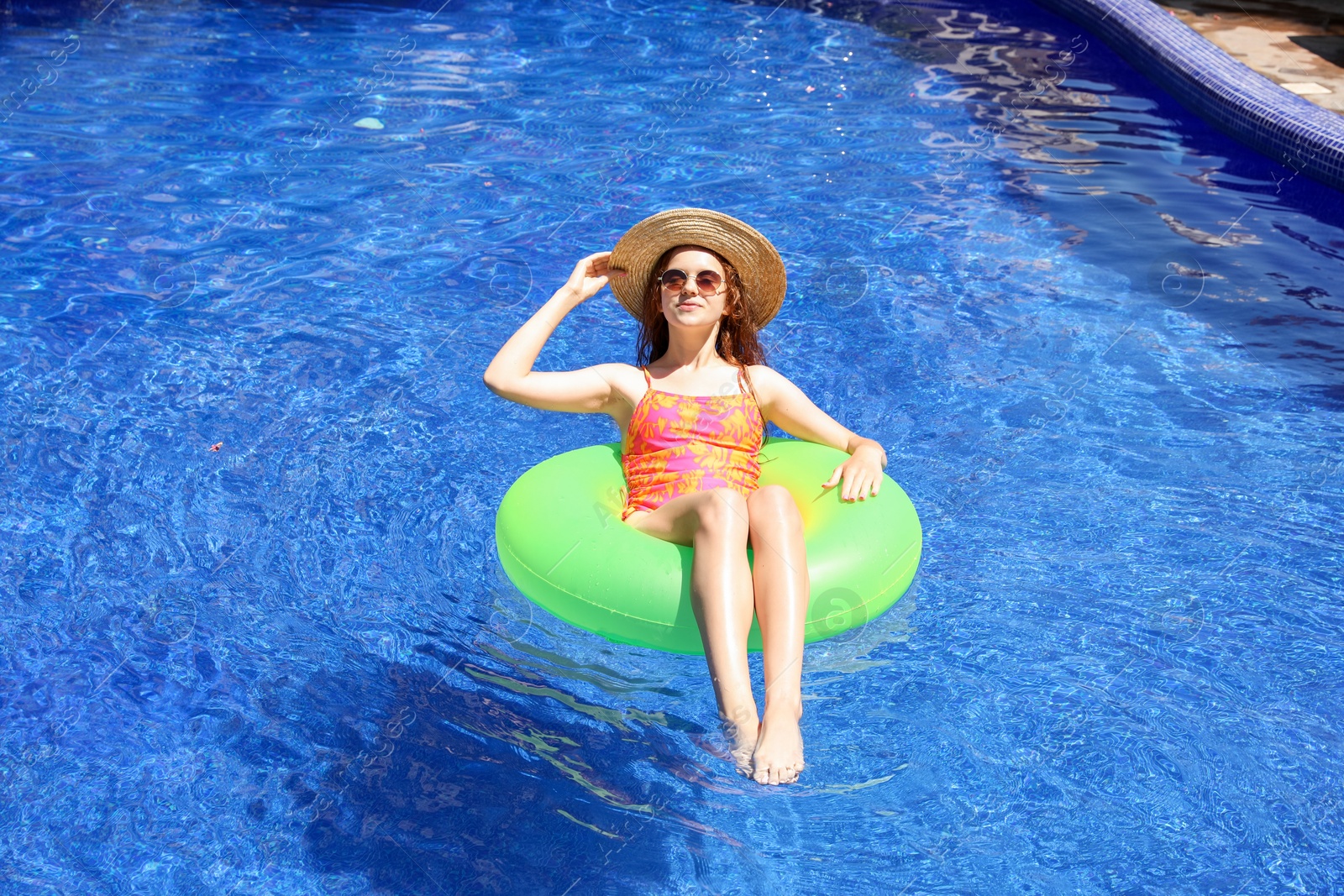 Photo of Girl on inflatable ring in swimming pool outdoors on sunny day