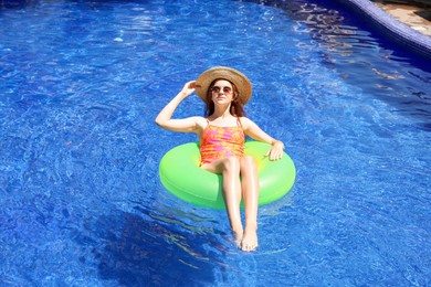 Photo of Girl on inflatable ring in swimming pool outdoors on sunny day