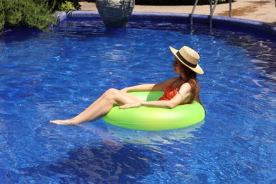 Photo of Girl on inflatable ring in swimming pool outdoors on sunny day