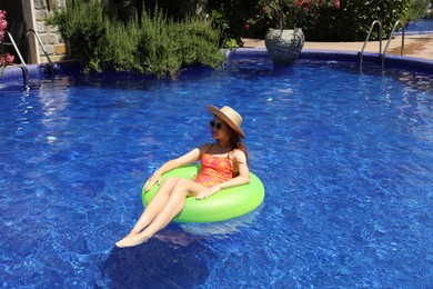 Photo of Girl on inflatable ring in swimming pool outdoors on sunny day