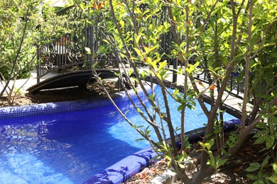 Photo of Outdoor swimming pool, bridge and different green plants