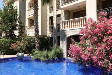 Photo of Outdoor swimming pool and different plants near hotel at luxury resort