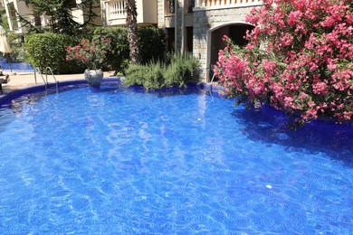 Photo of Outdoor swimming pool and different plants near hotel at luxury resort