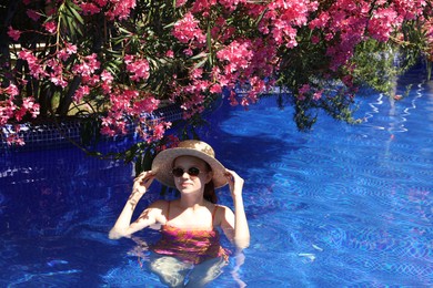 Photo of Girl with straw hat in swimming pool outdoors on sunny day, space for text