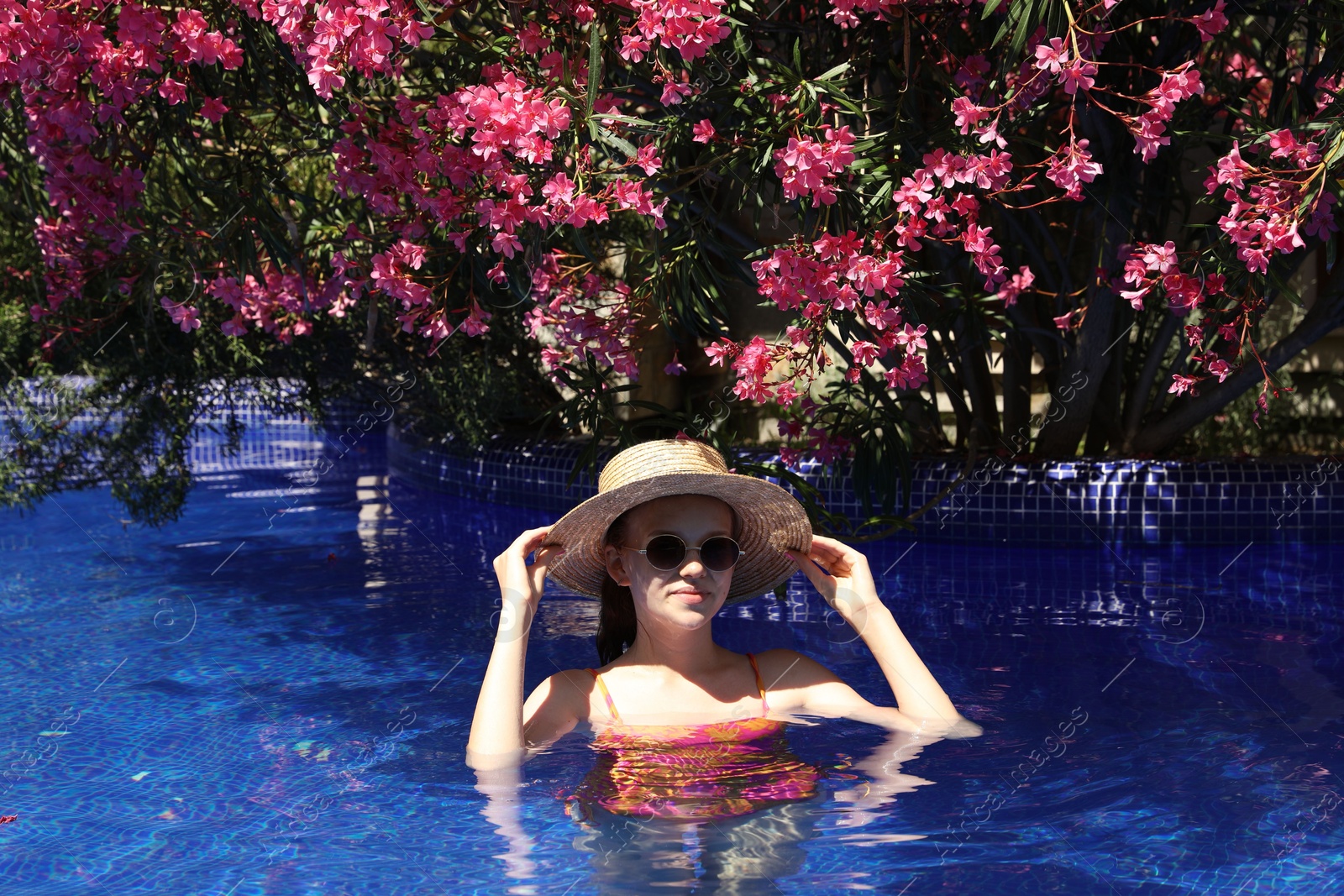 Girl with straw hat in swimming pool outdoors on sunny day Photo of Girl with straw hat in swimming pool outdoors on sunny day