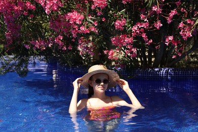 Photo of Girl with straw hat in swimming pool outdoors on sunny day