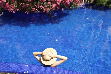 Photo of Girl with straw hat in swimming pool outdoors on sunny day, above view