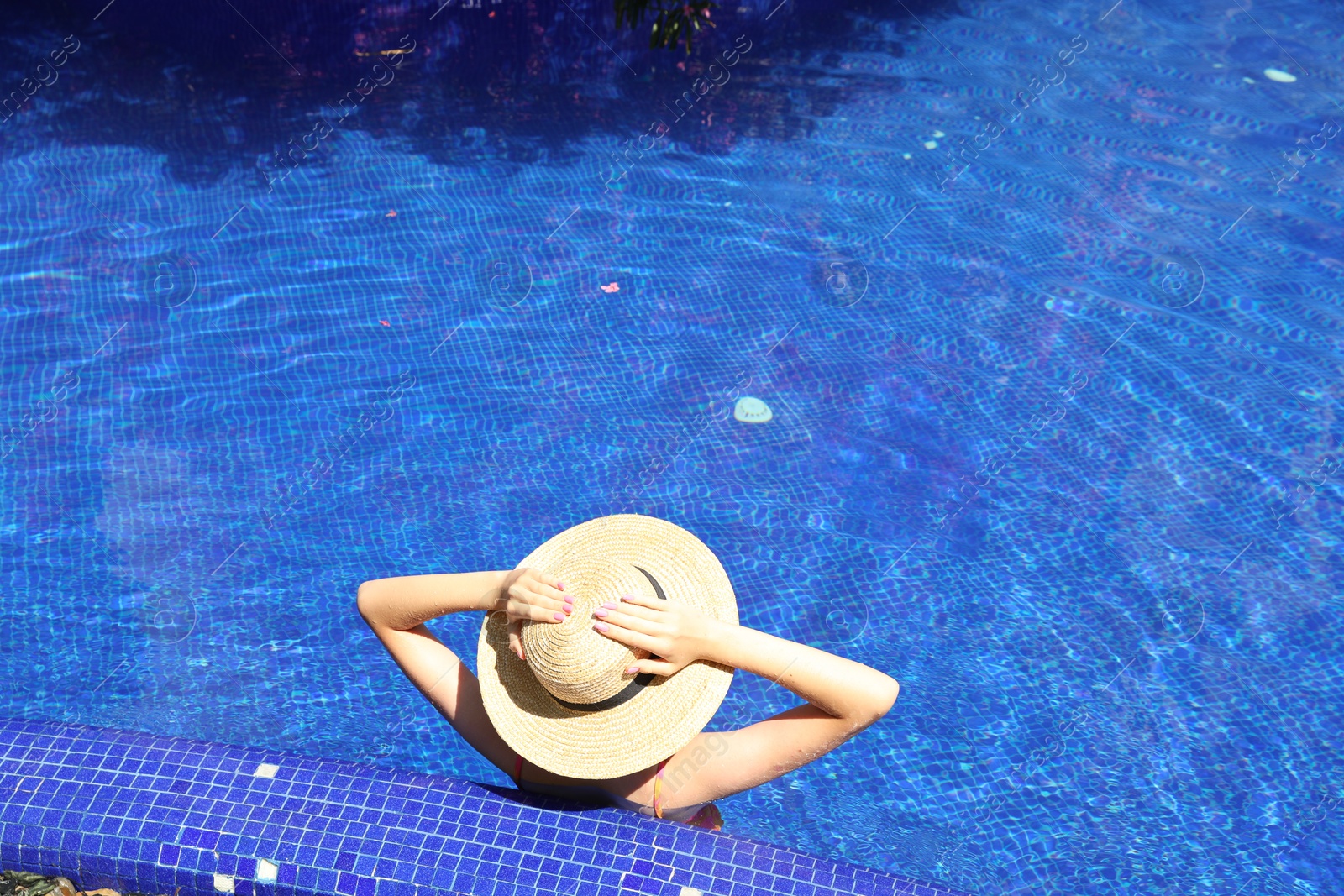 Photo of Girl with straw hat in swimming pool outdoors on sunny day, above view