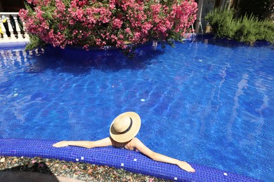 Photo of Girl with straw hat in swimming pool outdoors on sunny day, above view