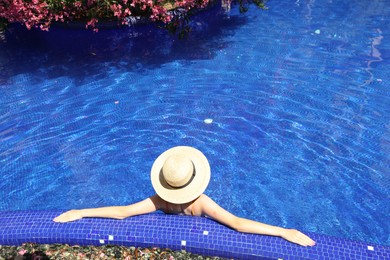 Photo of Girl with straw hat in swimming pool outdoors on sunny day, above view