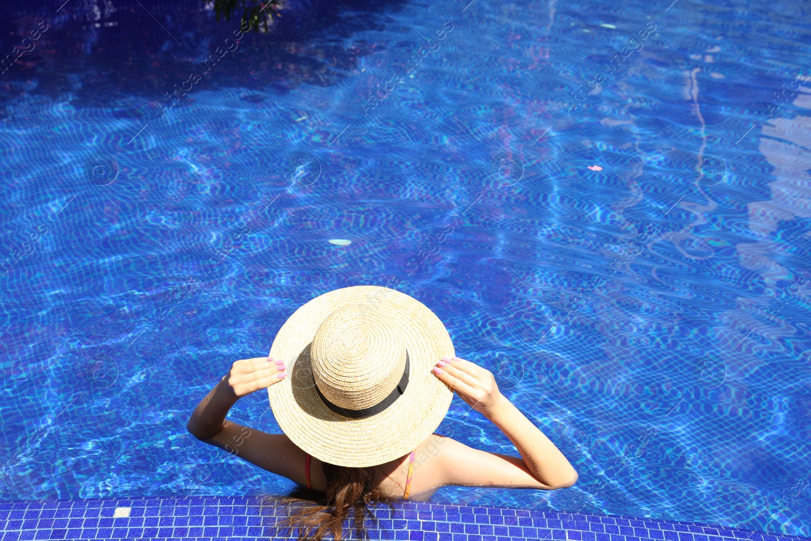 Photo of Girl with straw hat in swimming pool outdoors on sunny day, above view